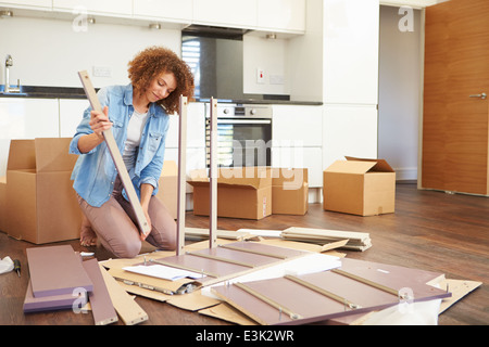 Woman Putting Ensemble mobilier d'auto assemblage in New Home Banque D'Images