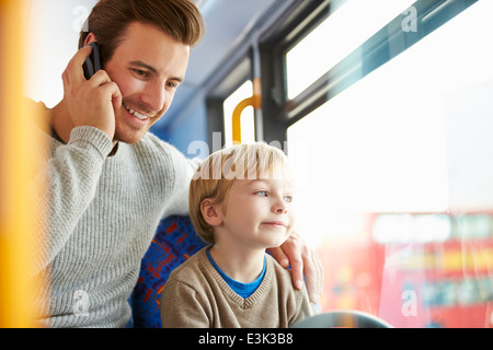 Père Using Mobile Phone On voyage en bus avec fils Banque D'Images