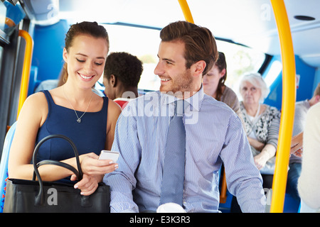 Businessman and Woman Looking At Mobile Phone On Bus Banque D'Images