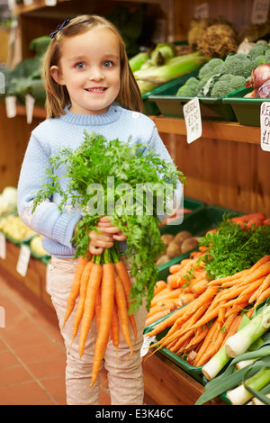 Young Girl Holding Bunch of Carrots in Farm Shop Banque D'Images