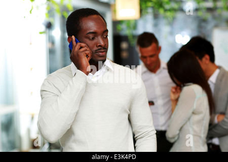 Portrait de l'Afrique de l'réfléchies sur le smartphone devant des collègues Banque D'Images