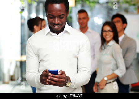 Happy businessman using smartphone devant des collègues Banque D'Images