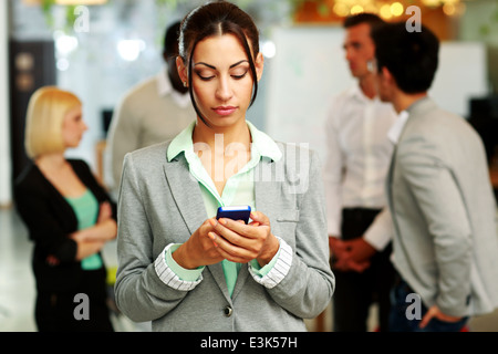 Portrait of a beautiful businesswoman using smartphone devant des collègues Banque D'Images