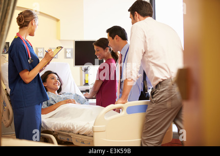Réunion de l'équipe médicale autour de Female Patient In Hospital Room Banque D'Images