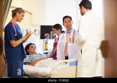 Réunion de l'équipe médicale autour de Female Patient In Hospital Room Banque D'Images