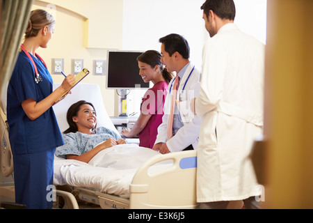 Réunion de l'équipe médicale autour de Female Patient In Hospital Room Banque D'Images