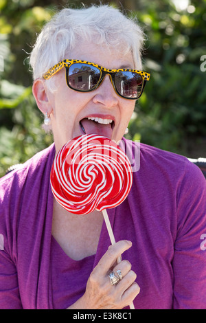Mature Woman in Sunglasses appréciant léchant sa sucette surdimensionné, USA Banque D'Images