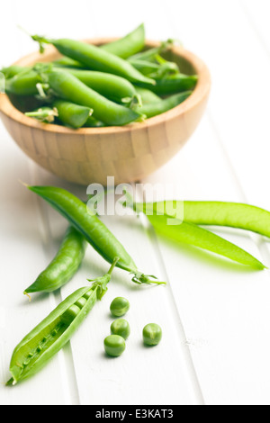 Gousse de pois vert sur blanc table table en bois Banque D'Images