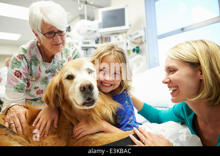 Jeune fille d'être visité à l'hôpital par chien de thérapie Banque D'Images