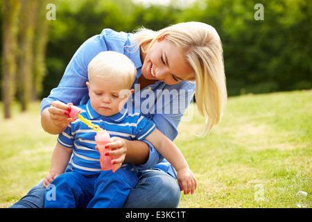 Mère Faire des bulles pour jeune garçon de jardin Banque D'Images