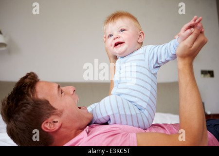 Père jouant avec son bébé qu'ils se trouvent dans le même lit Banque D'Images