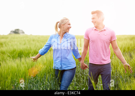 Romantic Couple Walking in Field Holding Hands Banque D'Images