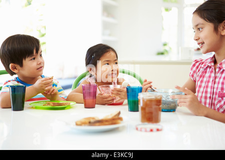 Trois enfants d'Asie ayant le petit déjeuner ensemble dans la cuisine Banque D'Images