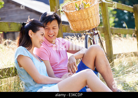 Asian Couple reposant par cycle à l'ancienne barrière Banque D'Images