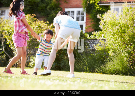 Mère asiatique jouant dans son jardin d'été avec les enfants Banque D'Images