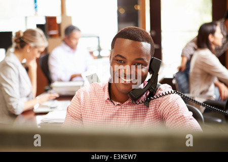 Businessman on téléphone au bureau avec en arrière-plan de réunion Banque D'Images