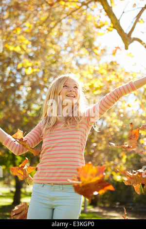 Jeune Fille de jeter les feuilles d'automne dans l'air Banque D'Images