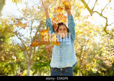 Jeune Fille de jeter les feuilles d'automne dans l'air Banque D'Images