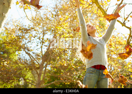 Woman Throwing les feuilles d'automne dans l'air Banque D'Images