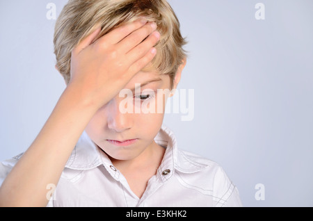 La douleur maux de tête main enfant garçon gens portrait ache malade triste fond gris gris beau stress mal déçu l'enfance Banque D'Images