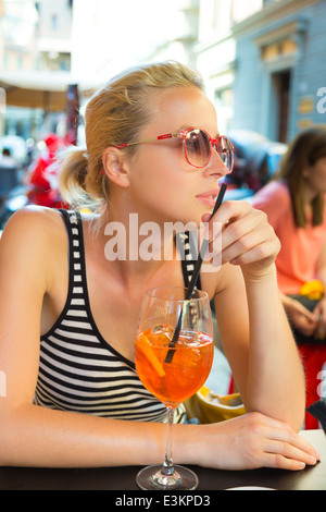 Femme avec cocktail au café de la rue. Banque D'Images