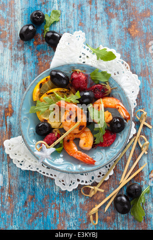 Crevettes grillées fruits et feuilles de roquette au fond rustique. Vue de dessus. Banque D'Images