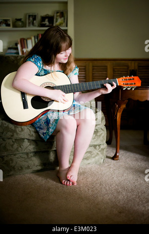 Photo de teenage girl (13-15) playing acoustic guitar at home Banque D'Images