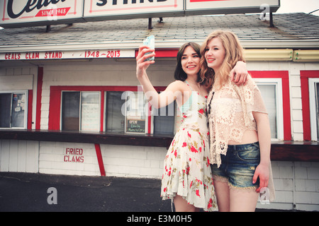 Photo de teenage girl (13-15) en tenant avec son ami selfies, New Hampshire, USA Banque D'Images