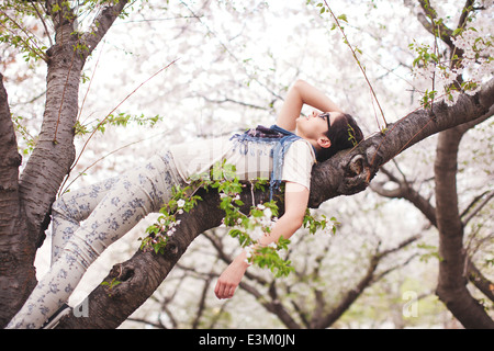 Photo of young woman lying on branch, Massachusetts, USA