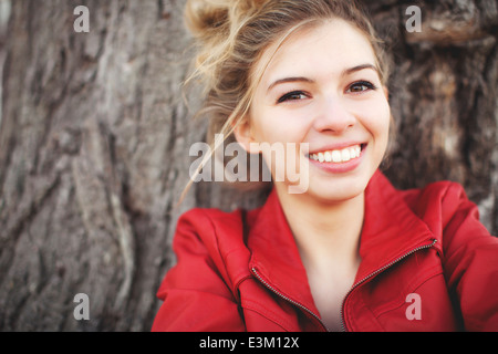 Portrait of smiling woman (18-19) contre l'arbre Banque D'Images