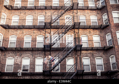 Jeune couple kissing on fire escape Banque D'Images