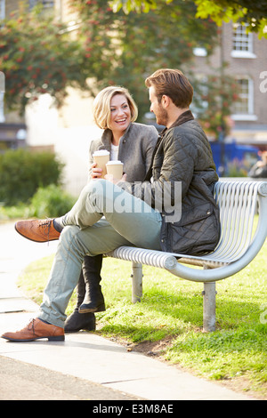 Couple Relaxing On Park Bench avec café à emporter Banque D'Images