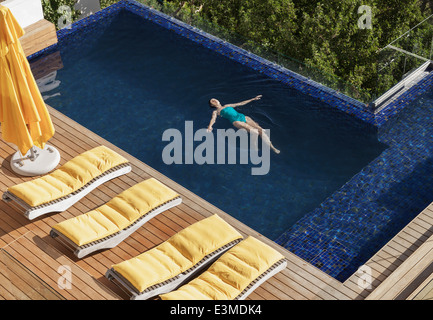 Femme flottant dans piscine de luxe Banque D'Images