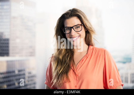 Portrait of smiling businesswoman in fenêtre urbaine Banque D'Images