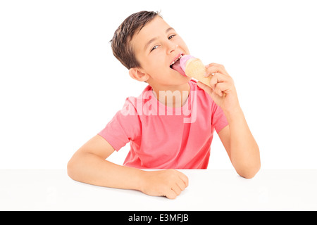 Joyeux petit garçon mangeant une glace assis à une table Banque D'Images