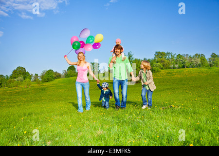 Famille heureuse marche avec ballons dans park Banque D'Images