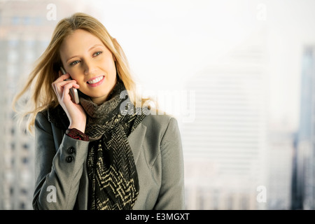 Businesswoman talking on cell phone in fenêtre urbaine Banque D'Images