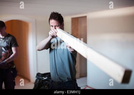 Male carpenter l'examen de planche en bois sur le site Banque D'Images