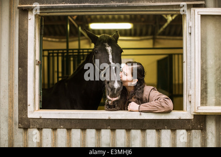 Young woman kissing horse stable en Banque D'Images