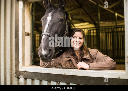 Portrait of happy young woman with horse stable en Banque D'Images