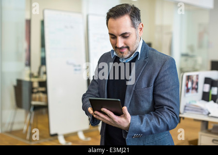 Mid adult businessman using digital tablet in office Banque D'Images