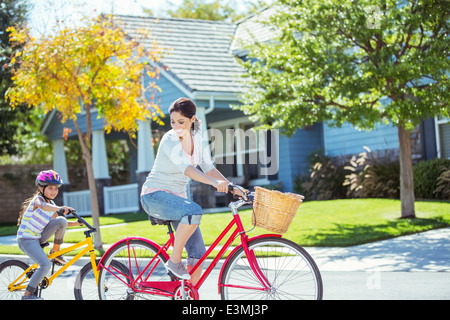 Mère et fille riding bikes in street Banque D'Images