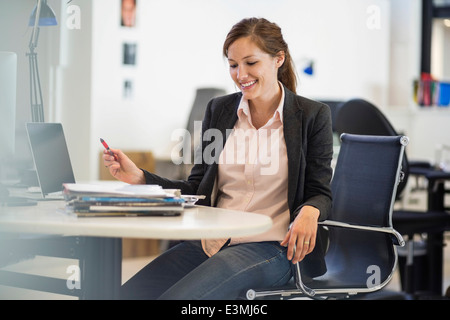 Smiling businesswoman working at desk in office Banque D'Images