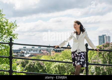 Senior woman looking away while standing contre railing Banque D'Images