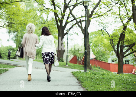 Vue arrière du senior female friends walking au chemin de jardin Banque D'Images