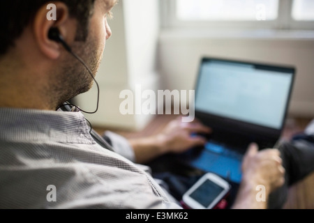 Mid adult businessman using laptop in office Banque D'Images