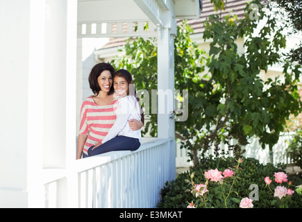 Portrait of smiling mother and daughter on porch Banque D'Images