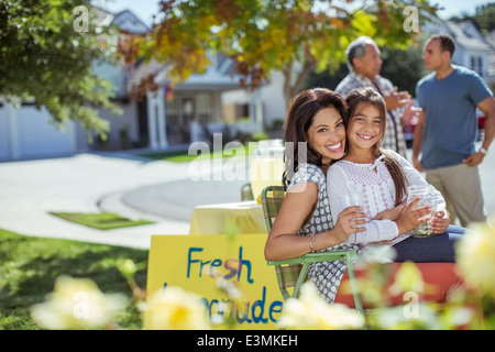 Portrait de Mère et fille hugging at lemonade stand Banque D'Images