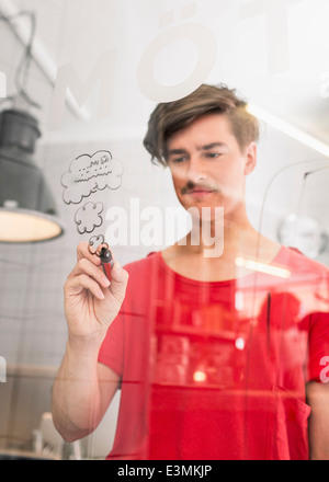 Jeune homme d'encombrement des nuages sur du verre transparent dans creative office Banque D'Images