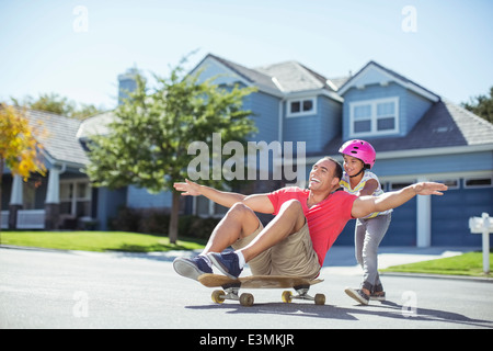 Fille père poussant sur planche Banque D'Images